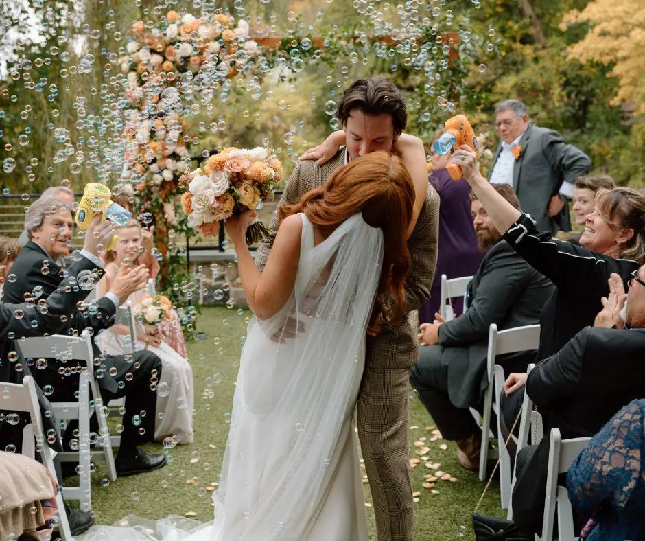 Nontraditional Songs for Recessional by Tess Schilke Bride and groom kissing down the aisle with bubbles floating in the air