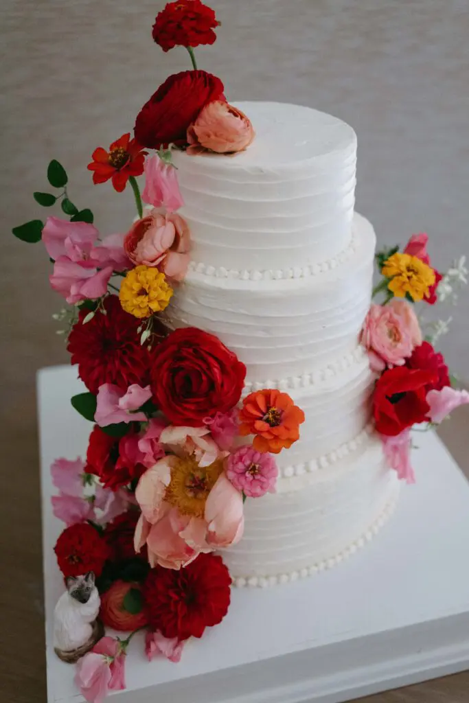 Wedding Cake with Florals by MLE Pictures White tiered wedding cake with pink yellow and red florals