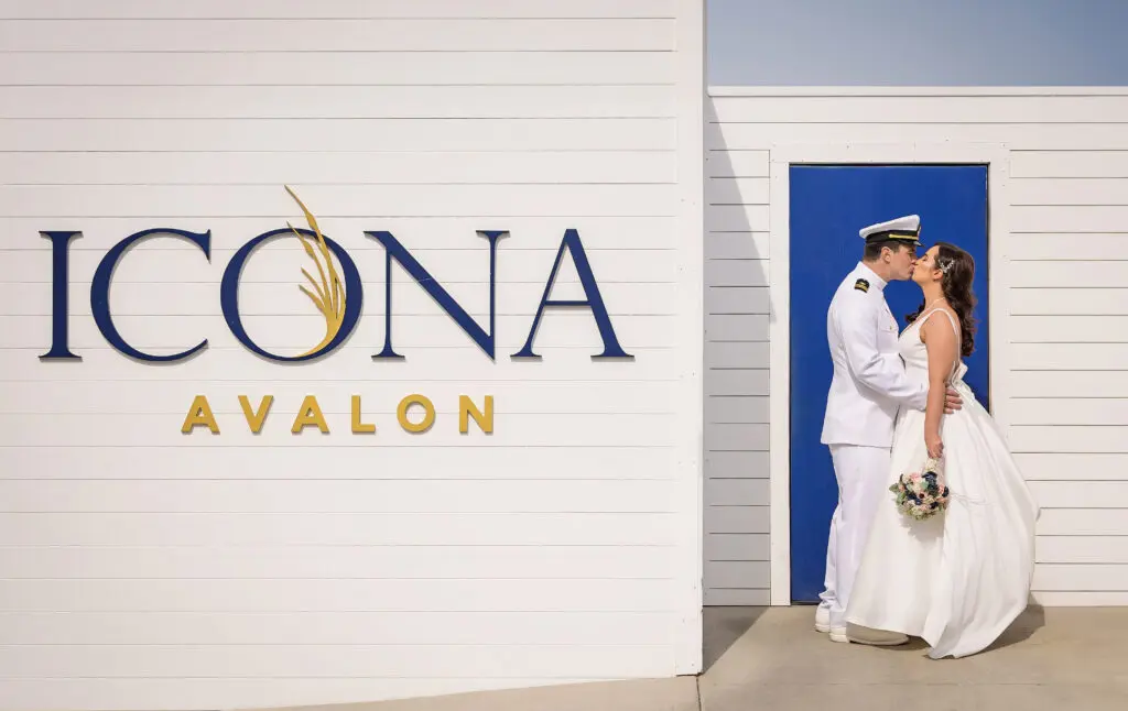 bride and groom kissing in front of sign that reads ICONA Avalon