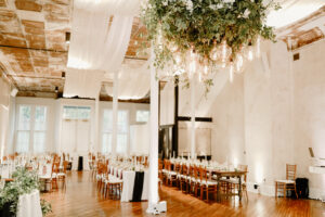 Reception hall decorated with white drapery and green plants 